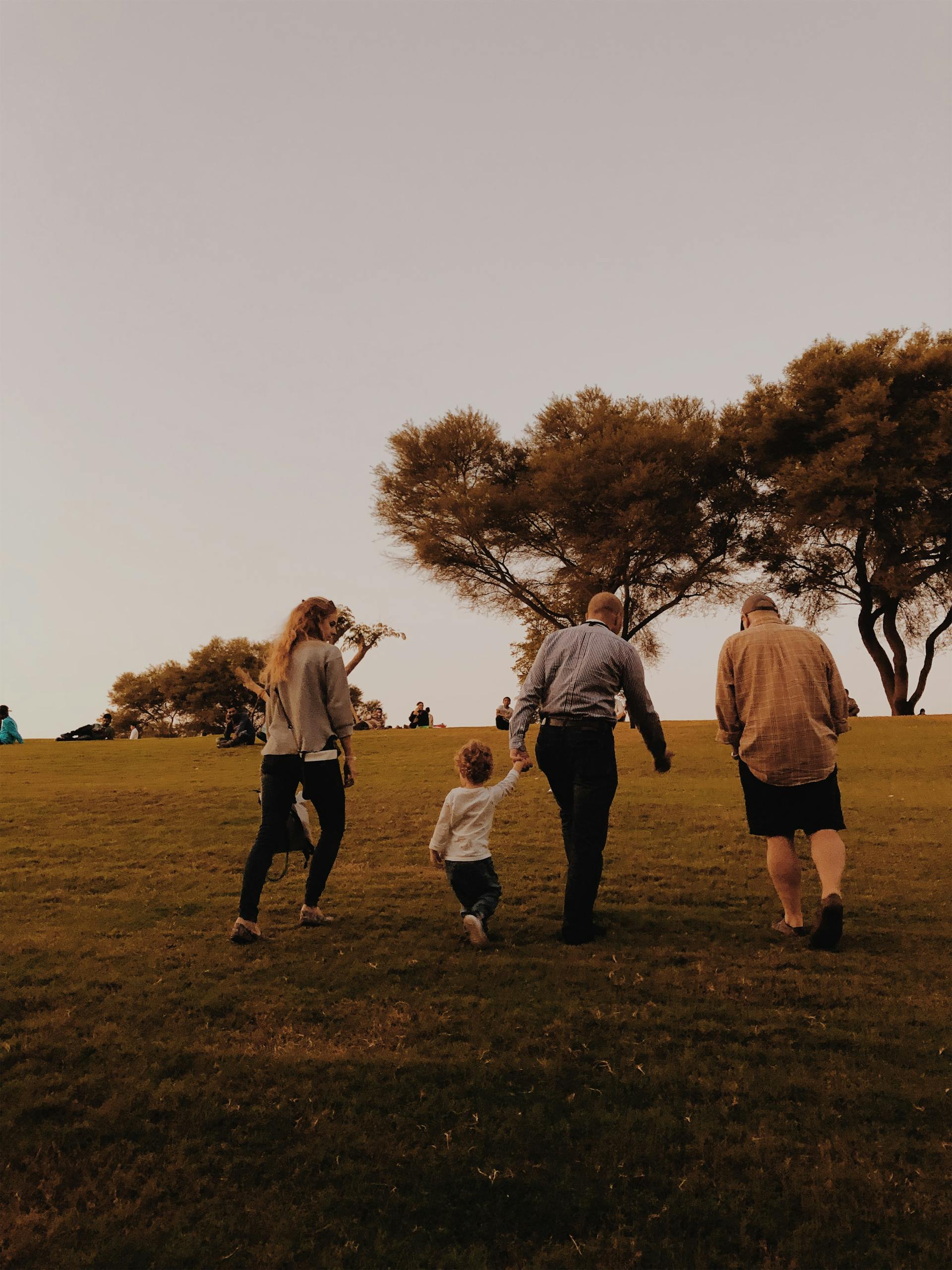 A family enjoying a relaxing walk in the park during sunset.