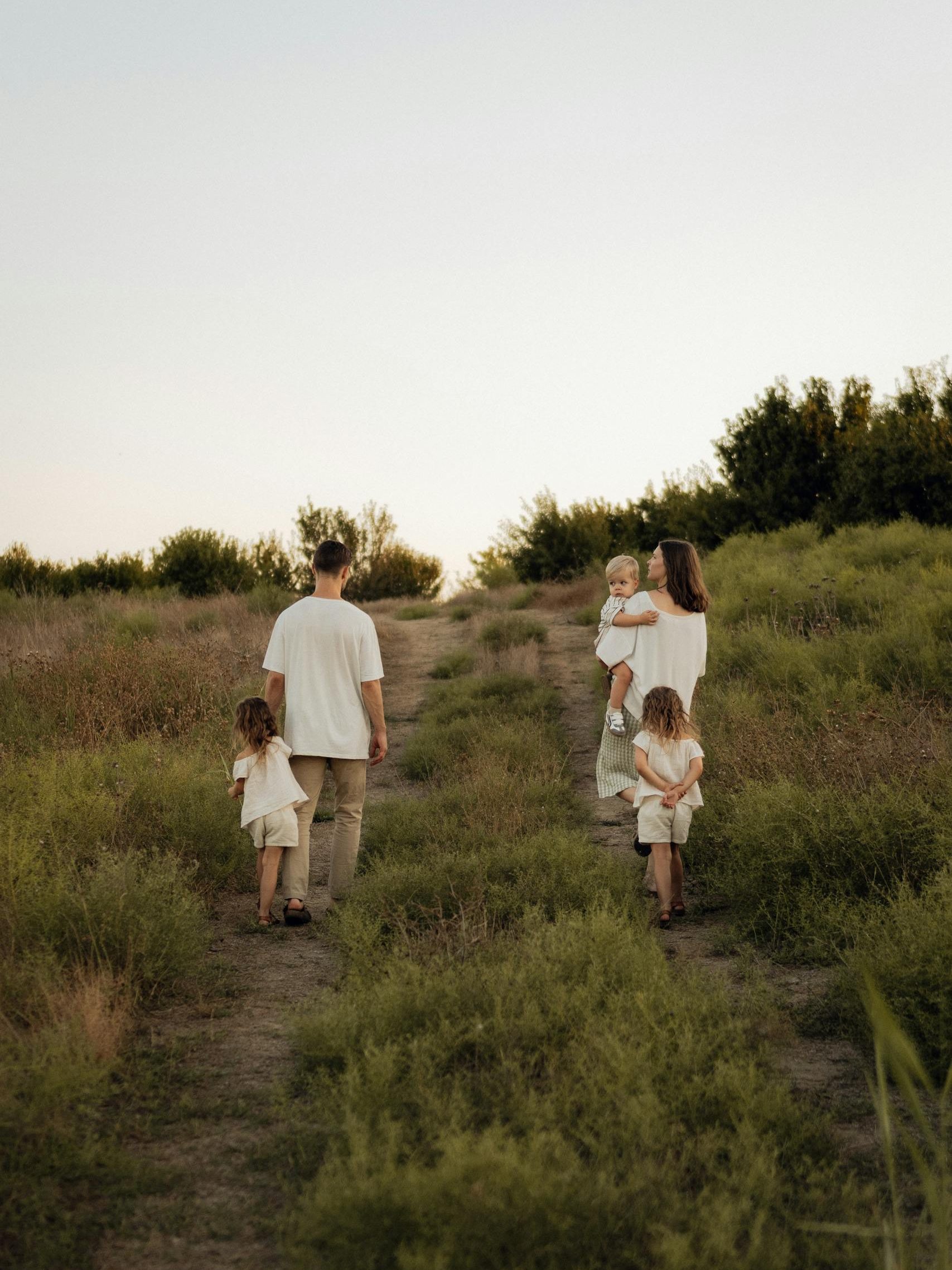A family walks on a green outdoor trail surrounded by nature, evoking togetherness and serenity.
