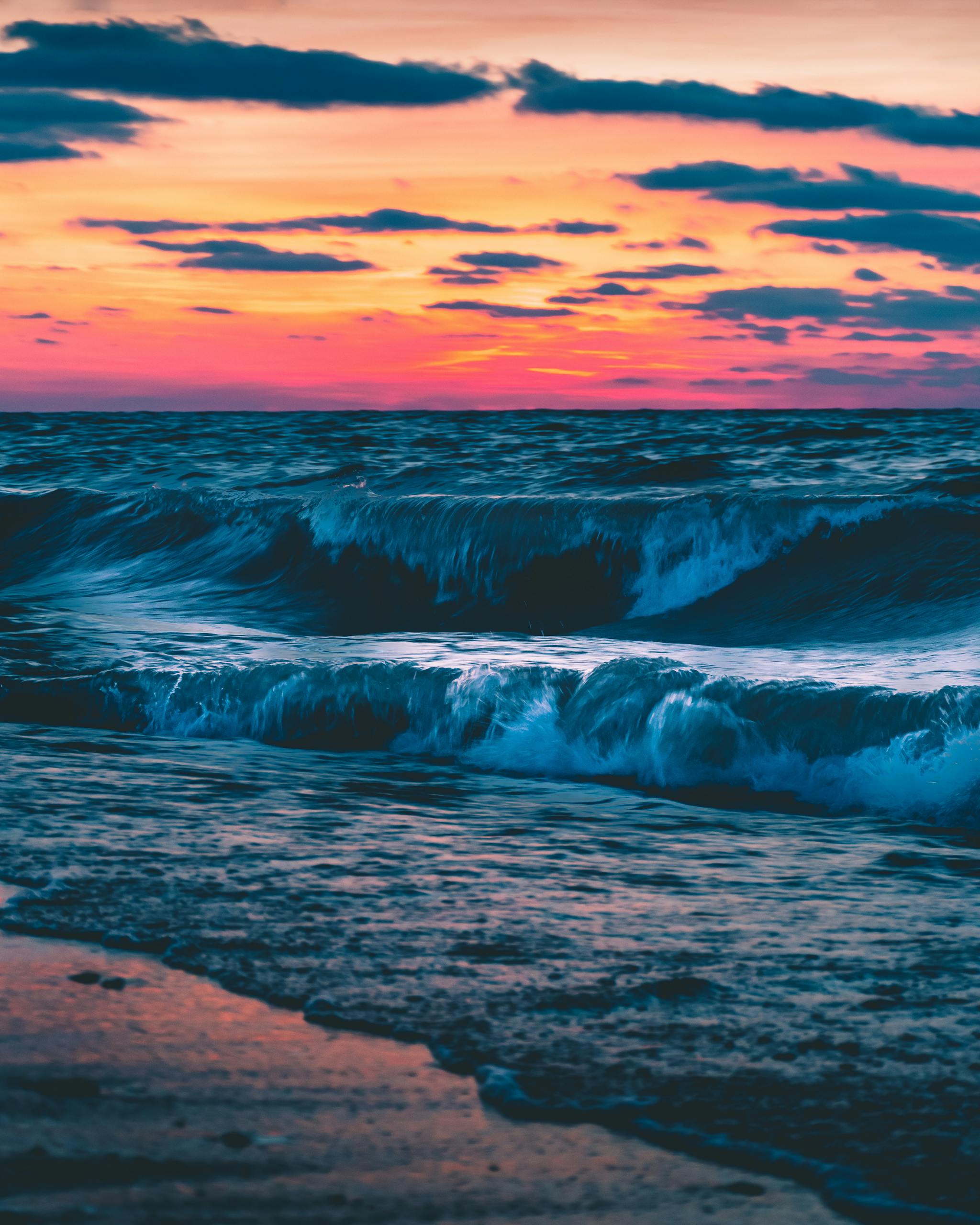 Captivating sunset casting vibrant hues over ocean waves at a beachside location.